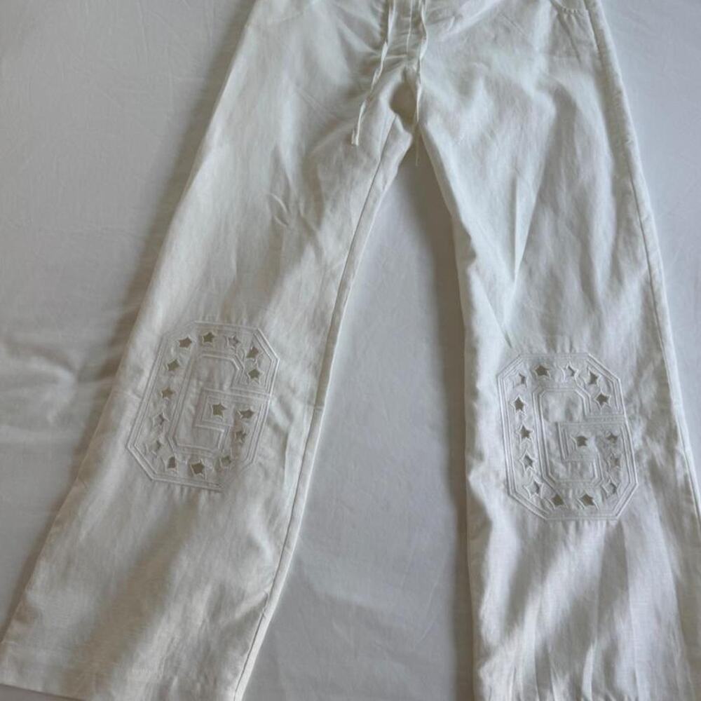 Gimaguas white linen pants with embroidered star patterns on the knees